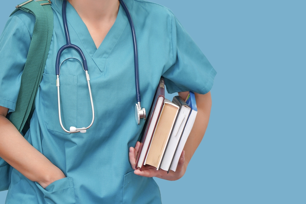 nurse in blue scrubs with books and a stethoscope