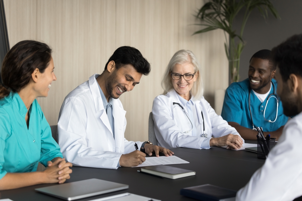 healthcare professionals signing contracts and risk management smiling in white and green scrubs at a table