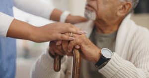 elderly patient and healthcare worker touch hands 